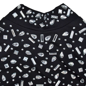 Gros plan du col en tricot noir orné de cristaux facettés et de strass brillants