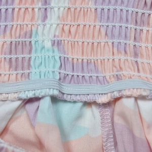 Detail of smocked elastic waist showing abstract colorful prints on the jumpsuit fabric