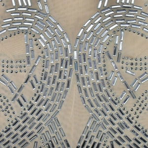 Dettaglio del vestito in rete velata con ricami intricati di strass e paillettes argento