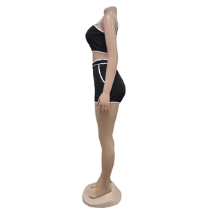 Detail view of black athletic two-piece set with white contrast piping on fabric