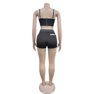Detail view of the back zipper closure and white piping on black two-piece shorts set