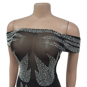 Détail de la mini robe en maille noire à épaules dénudées avec des strass argentés