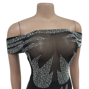 Gros plan de la robe en maille noire avec des motifs de flammes en strass argentés