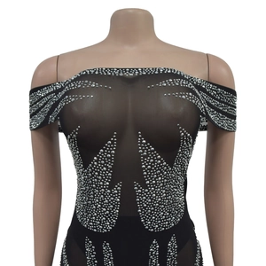 Détail d'un body en résille noire transparente avec motifs flammes en strass et épaules nues