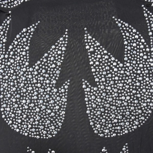 Détail macro de maille noire ornée de strass argentés scintillants en motifs d'ailes