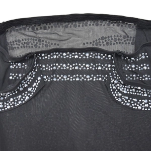 Détail du tissu en maille noire avec strass argentés brillants et motif à pois