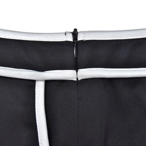 Detail of invisible zipper and contrast white stitching on a black two-piece set