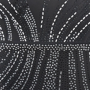 Close-up of sparkling silver and black rhinestones in a geometric pattern on black dress fabric