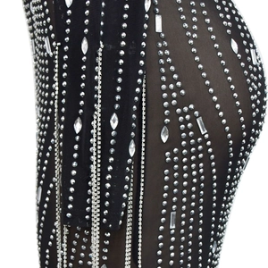 Détail d'une robe en résille noire avec strass scintillants et finitions à franges brillantes