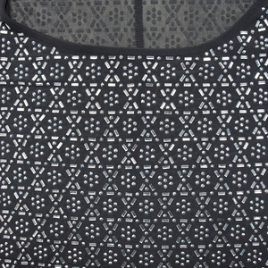 Dettaglio dell'abito in rete nera con strass argentati e motivi geometrici con borchie