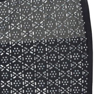 Dettaglio del tessuto a rete nera trasparente con motivi geometrici in strass