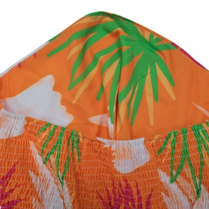 Detail of tropical print dress showing orange smocked fabric and palm leaf pattern