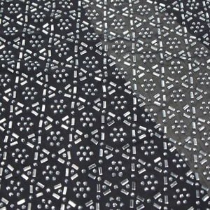 Dettaglio macro del tessuto a rete nero con motivi geometrici di strass argento