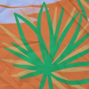 Close-up of tropical palm leaf print fabric in vibrant orange and green hues