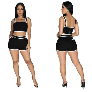 Detail view of women's black two-piece set featuring contrast white piping and back zipper