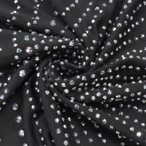 Close-up of black elastic fabric with sparkling silver rhinestones showing drape and texture