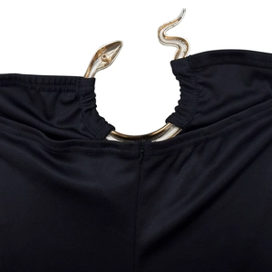 Detail of elegant gold snake-shaped metal ring on a black knit jumpsuit neckline
