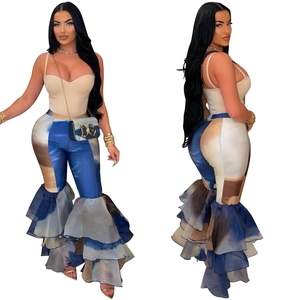 Détail du pantalon évasé avec motifs tie-dye bleus et ourlets à volants en maille