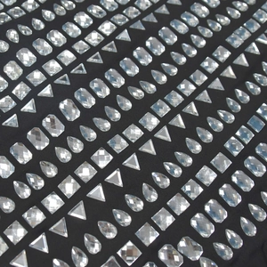 Detailed view of mixed-shape rhinestone crystals on black fabric for fashion garments
