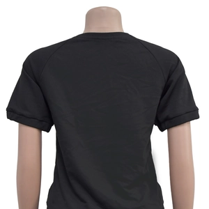 Detail view of the back of a black raglan short sleeve T-shirt with a round neckline