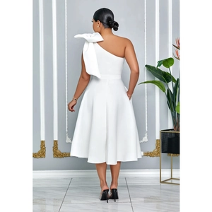 Detail eines weißen One-Shoulder-Midikleids mit einer großen dekorativen Schleife an der Schulter