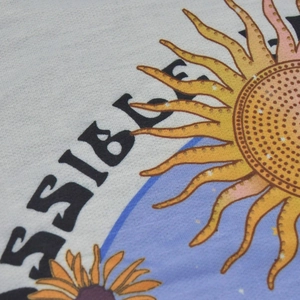 Close-up of retro sun and sunflower print on cream cotton knit short sleeve T-shirt
