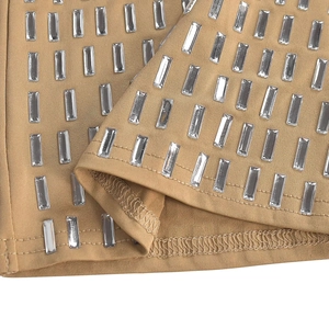 Close-up of khaki sleeveless dress featuring sparkling rhinestone embellishments and seam details