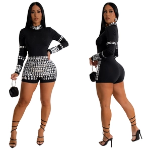 Detail of black long-sleeve romper featuring geometric silver rhinestone embellishments