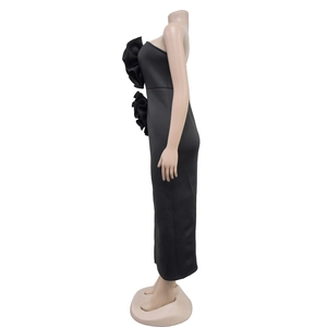 Detail view of solid black slim-fit dress featuring 3D floral accent and side slit