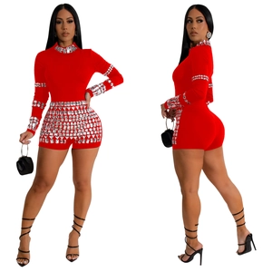 Close-up of red long-sleeve romper with intricate silver rhinestone geometric patterns