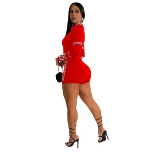 Detailed view of the sparkling rhinestone trim on a red long-sleeve party romper