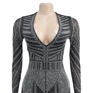 Détail d'un body noir à col en V avec strass argentés et manches en maille transparente