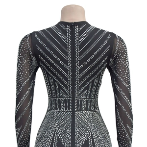 Détail de robe noire à strass avec manches en mesh et motif géométrique brillant