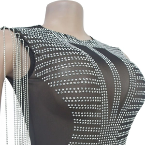 Detail of black mesh dress featuring silver rhinestone patterns and long chain fringe