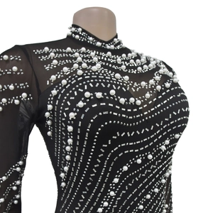 Close-up of black mesh dress featuring intricate white pearl and rhinestone wave patterns