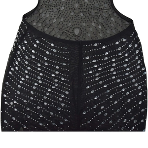 Détail du tissu en maille noire avec des strass en cristal étincelants sur la robe