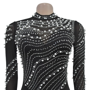 Close-up of black mesh fabric with intricate white pearl and silver rhinestone embroidery