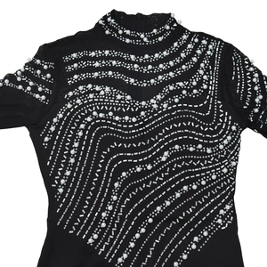 Close-up of black long-sleeved dress with sheer mesh, wave pearls and rhinestones decoration