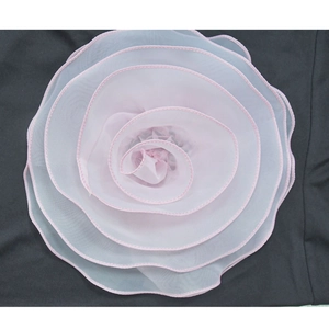 Close-up of pink 3D floral applique with multi-layered petals on contrasting dark fabric
