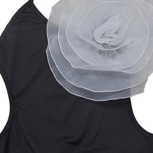 Detailed close-up of a large white 3D organza flower on a black strap dress