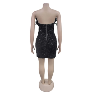 Close-up of back zipper closure on black sequined dress with feather accents