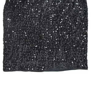 Close-up of black sequin fabric texture with reflective metallic circles on the dress