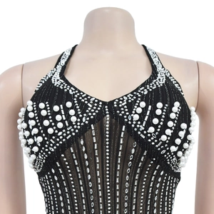 Detailed close-up of a black halter top featuring white pearls and sparkling rhinestones