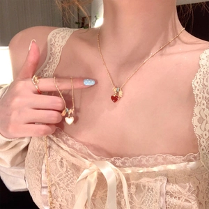 Elegant gold necklace featuring a red heart pendant and matching ring on model