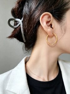 Close-up of golden S925 sterling silver hoop earrings with textured finish worn by a model