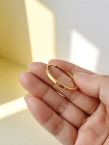 Close-up of golden geometric faceted bangle bracelet held to show texture and size