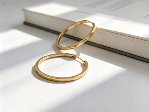 Detail of S925 sterling silver faceted gold earrings leaning against a white book