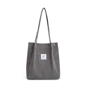 Detail view of corduroy tote bag showing gray ribbed texture and feather label