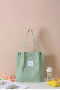 Detail of light green corduroy tote bag featuring magnetic snap closure and soft texture
