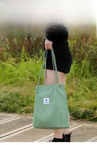 Detail of light green corduroy tote bag showing vertical texture and durable handles
